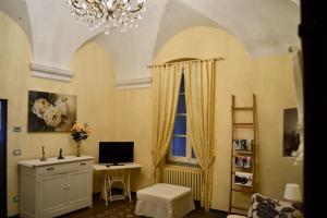 a living room with a chandelier and a desk and a window at Appartamento Ligure nel centro storico in Finale Ligure