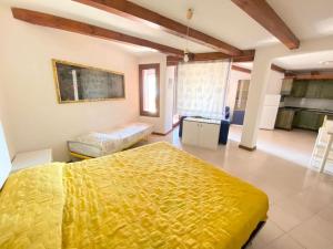 1 dormitorio con 1 cama amarilla y cocina en Capo Coda Cavallo vista mare, en Capo Coda Cavallo