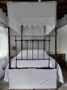 Cama negra con colcha blanca y dosel en Faith's Stone House, en Simou