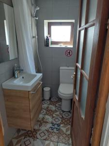 een badkamer met een wastafel, een toilet en een raam bij Faith's Stone House in Simou