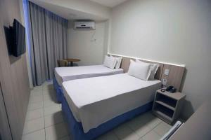 a hotel room with two beds and a television at Hotel da Costa By Nobile in Aracaju