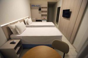 Hotel da Costa By Nobile في أراكاجو: غرفة صغيرة بسريرين وكرسي
