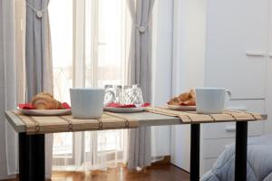 une table avec deux tasses et des assiettes de nourriture dans l'établissement ApuliaLux Prana Home - Bari City Center, à Bari