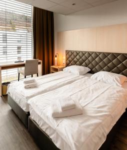 una camera da letto con un grande letto con asciugamani bianchi di Los Lorentes Aparthotel Bern Airport a Belp