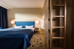ein Schlafzimmer mit einem blauen Bett in einem Zimmer in der Unterkunft Baltic Zinnowitz - Hotel mit Meerwasserpool und Thermalbad in Zinnowitz