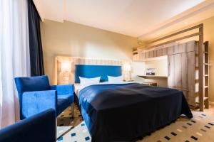 Habitación de hotel con 1 cama y 2 sillas azules en Baltic Zinnowitz - Hotel mit Meerwasserpool und Thermalbad, en Zinnowitz