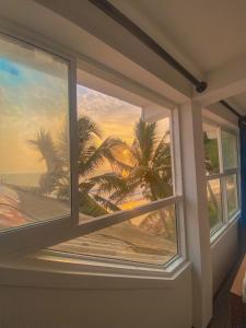 a window with a view of the beach and palm trees at Indika Beach Villa in Galle