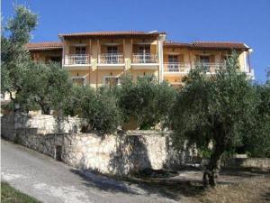 a building with trees in front of a stone wall at Sofos Apartments in Tsilivi