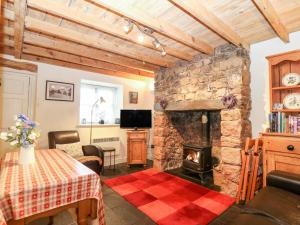 a living room with a stone fireplace and a table at White Lilac Cottage in Llanfairpwllgwyngyll