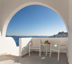 een tafel en stoelen onder een boog met uitzicht op de oceaan bij Andromeda Resort in Astypalaia-stad (Chora)