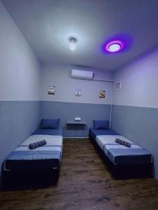 a room with two beds and a purple light at Doyar's Home Stay (Palm Garden -1st Floor) in Lahad Datu