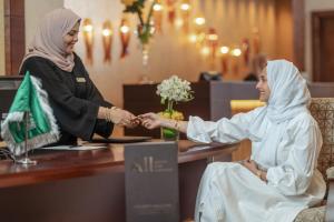 een vrouw schudt de hand met een vrouw aan een tafel bij Raffles Makkah Palace in Mekka