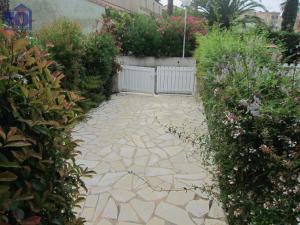 a stone walkway in a garden with plants and flowers at Maison Valras-Plage, 3 pièces, 6 personnes - FR-1-781-6 in Valras-Plage