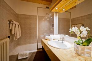 y baño con lavabo y bañera. en Hotel les Flocons, en Courchevel