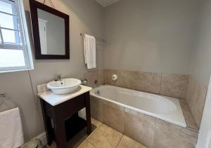 a bathroom with a sink and a bath tub at Sir Roys Guesthouse At The Sea in Port Elizabeth +34 photos