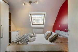 a bedroom with a white bed with a red wall at Modern duplex apartment near the beach in Middelkerke
