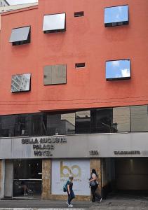 dos personas caminando en frente de un edificio rojo en Bella Augusta Hotel, en São Paulo