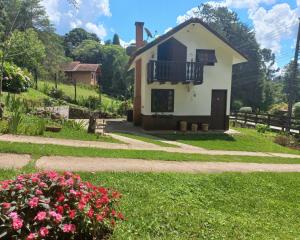 een huis met een balkon en bloemen in de tuin bij Recanto Boreal - Monte Verde in Monte Verde