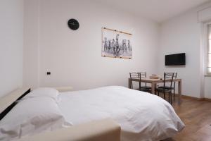 Dormitorio blanco con cama y mesa en Bonomelli Home con posto auto Fondazione Prada en Milán