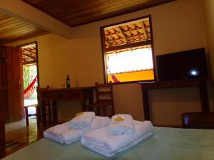 um quarto com três toalhas dobradas numa mesa em pousada no caminho do escorrega em Visconde de Mauá