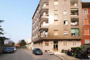 un edificio de apartamentos con coches estacionados frente a él en Bonomelli Home con posto auto Fondazione Prada en Milán