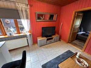 uma sala de estar com paredes vermelhas e uma televisão de ecrã plano em Apartment Holzhaus em Cuxhaven