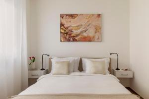 Un dormitorio con una cama blanca con un cuadro encima. en Lake Modern Suites - Free Parking, en Lugano