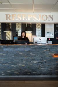 a woman sitting at a reception desk in an office at Vestnes Fjordhotell in Vestnes