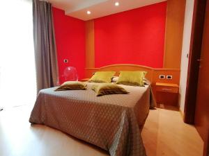 a bedroom with a bed with a red wall at Hotel Luis in Fiera di Primiero