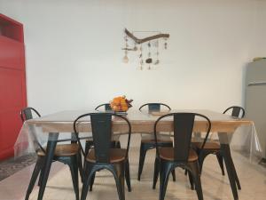 een eettafel met 4 stoelen en een witte muur bij Maison de village proche de l'étang et de la mer in Marseillan