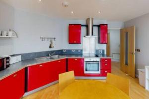 una cucina con armadi rossi e tavolo giallo di 2 Bed Flat Centre of Lace Market a Nottingham