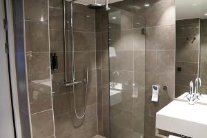 a shower with a glass door next to a sink at Vimmerby Stadshotell, WorldHotels Crafted in Vimmerby