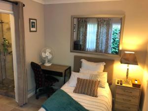 1 dormitorio con cama, escritorio y espejo en Self Catering Guest House, en Ciudad del Cabo