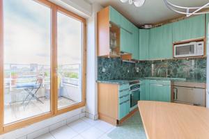 une cuisine avec des placards verts et une grande fenêtre dans l'établissement Résidor - Apartment 4P La Villette Park, à Paris