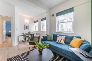 a living room with a blue couch and a table at Kula London - Tower Bridge in London