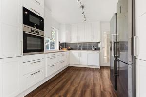 a white kitchen with white cabinets and a refrigerator at Fint hus i Flåm in Aurland