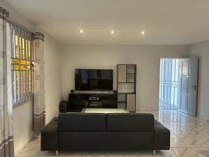 a living room with a black couch and a flat screen tv at Appartement Hematiet in Paramaribo