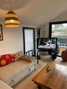 a living room with a couch and a flat screen tv at Samui - Equipé borne de recharge - Powering Station Electric Car in Capbreton