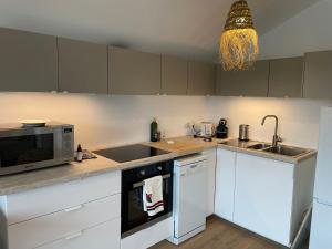 a kitchen with white cabinets and a microwave at Samui - Equipé borne de recharge - Powering Station Electric Car in Capbreton