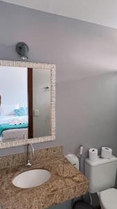 y baño con lavabo, espejo y aseo. en Pousada Estalagem dos Corais da Prainha, en Arraial do Cabo