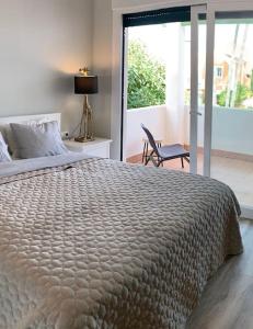 een slaapkamer met een bed, een stoel en een raam bij Modern beachside townhouse w/ private pool in Marbella
