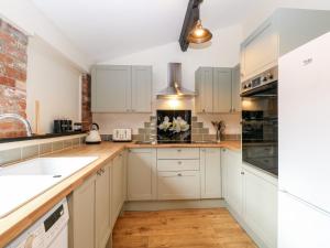 a kitchen with white cabinets and wooden floors at Squirrel Lodge in North Walsham