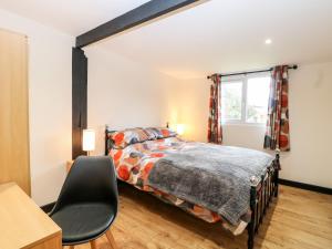 a bedroom with a bed and a chair at Squirrel Lodge in North Walsham