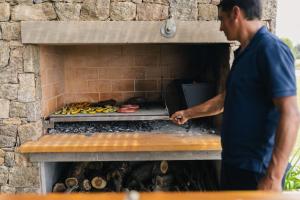 a man standing in front of a brick oven at La MaSia in Balneario Buenos Aires
