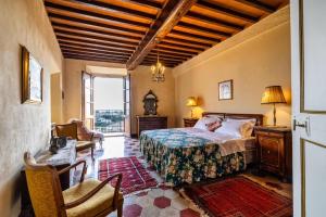 1 dormitorio con 1 cama, 1 silla y 1 ventana en Castello di Sovicille - Residenza d'Epoca, en Sovicille