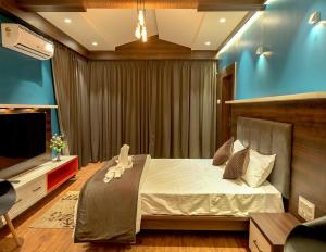 een slaapkamer met een bed en een flatscreen-tv bij Hotel Limelight in Kudāl