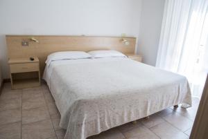 1 dormitorio con 1 cama grande con manta blanca en Hotel Eden, en Toscolano Maderno
