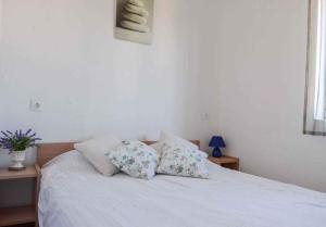 un letto bianco con due cuscini sopra di Apartment in Njivice - Insel Krk 47349 a Njivice