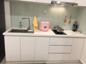 a white kitchen with a sink and a counter at Vinhome Grand Park Homestay in Long Bình