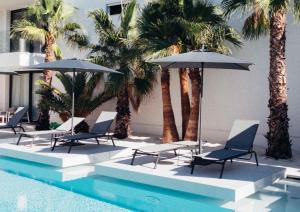 un grupo de sillas y sombrillas junto a una piscina en Vibra Experience Moorea, en Lido di Jesolo